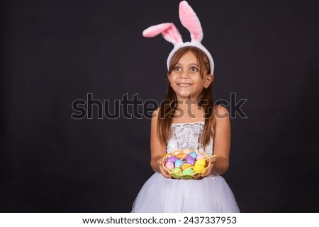 Cute little girl wearing bunny ears on Easter day. Girl holding basket with painted eggs. Royalty-Free Stock Photo #2437337953