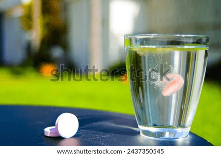 Dissolving orange vitamin tablet in a glass of water