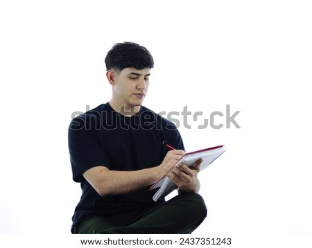 Image of a concentrated young man writing in a notebook, ideal for representing study, work or business concepts. White background for easy editing
