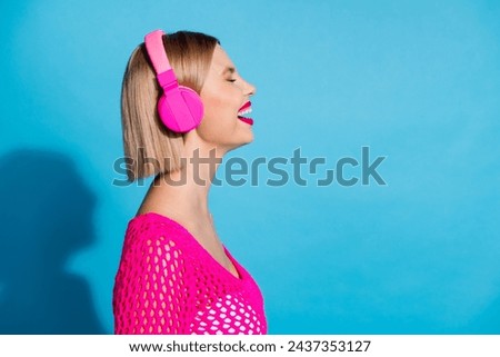 Photo portrait of pretty young girl profile headphones sing good mood wear trendy pink knitwear outfit isolated on blue color background
