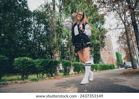 Full body photo of charming teenager woman walking touch specs cheerful wear trendy uniform clothes nature green park background
