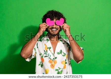 Photo of positive cool latin guy dressed print shirt two pink heart postcards close eyes isolated green color background