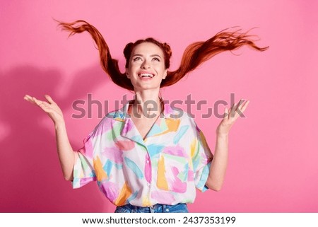 Portrait of cheerful woman wear print shirt hands fluttering foxy hair look up at logo empty space isolated on pink color background Royalty-Free Stock Photo #2437353199