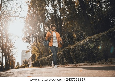 Photo of cheerful glad man dressed stylish clothes walking in park going college sunny day outside