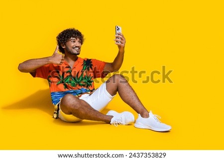 Full size photo of satisfied man dressed print shirt making selfie on smartphone show thumb up isolated on yellow color background