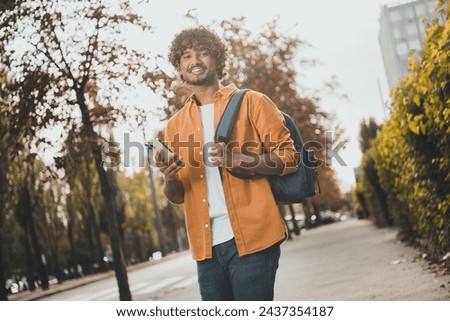 Photo of cheerful latin man dressed stylish clothes holding modern device phone going shopping spring outside