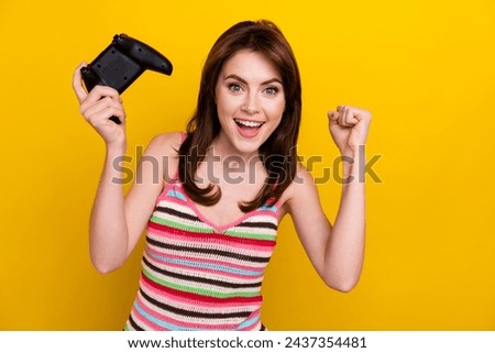 Photo of overjoyed girl with stylish hairdo wear striped tank hold joystick win match in video game isolated on yellow color background