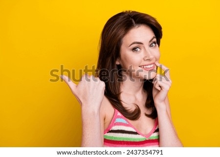 Portrait of good mood woman wear knit tank directing at proposition empty space finger on lip isolated on vivid yellow color background