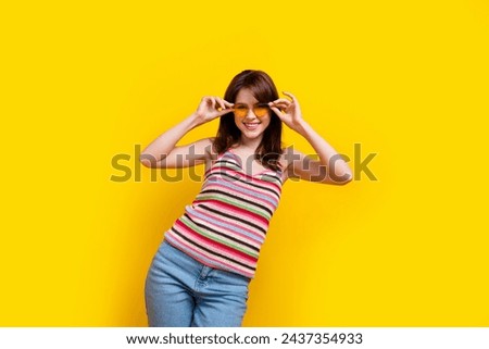 Portrait of optimistic pretty woman dressed knitwear top touching sunglass look at summer sale isolated on yellow color background