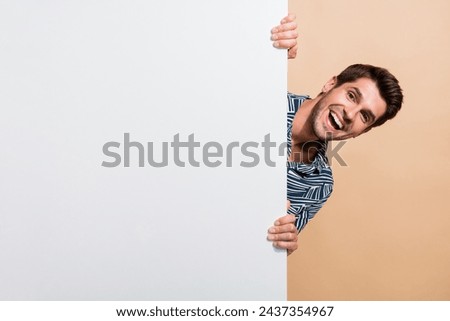 Photo portrait of amazed positive guy hiding behind white wall blank unexpected such a good proposition isolated on beige color background