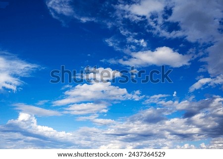 Fluffy white cumulus clouds with some cumulostratus  formations on a late summer afternoon are contrasted against the Australian sky creating a fascinating cloud scape with darker rain clouds. Royalty-Free Stock Photo #2437364529