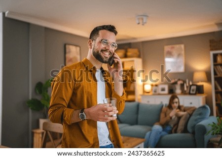 One adult man with eyeglasses stand at home use mobile phone talk Royalty-Free Stock Photo #2437365625