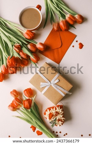 Craft gift box with a bow, a bouquet of tulips and an envelope, festive background.