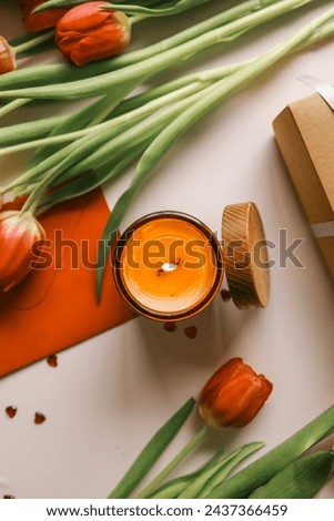 Beautiful spring background, burning candle, red tulips, gift box and cake.