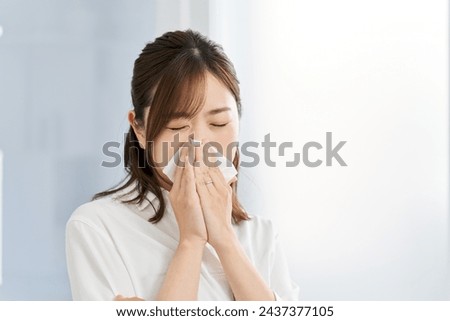 A woman blowing her nose due to rhinitis Royalty-Free Stock Photo #2437377105