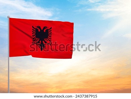 3D illustration of a Albania flag extended on a flagpole and in the background a beautiful sky with a sunset