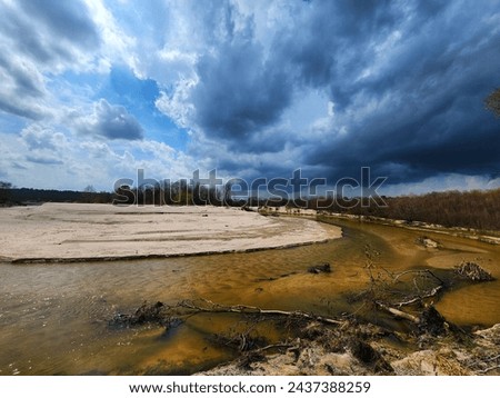 This is a picture of a thunderstorm, rolling over the bank of a large river.
