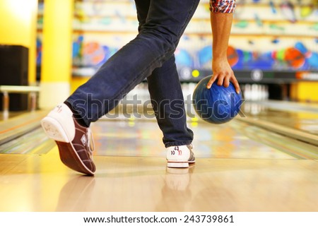 Male legs and bowling ball in alley background