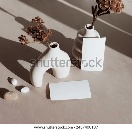 Blanks paper mockup ,modern beige vasen with dry grass , sunlight shadow  on beige background.Copy space.
Card Mockup,branding.