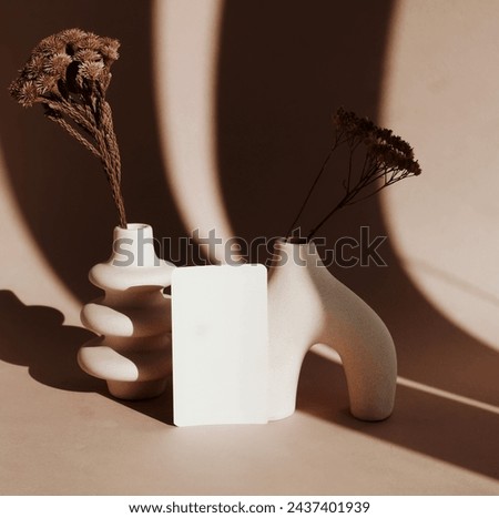 Blank paper mockup ,modern beige vasen with dry grass , sunlight shadow  on beige background.Copy space.
Card Mockup,branding.
