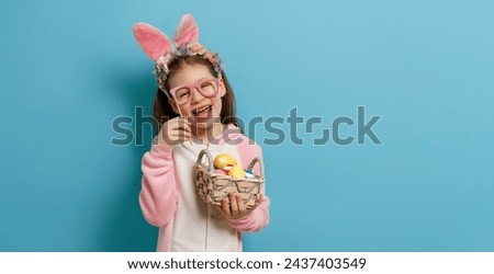 Cute little child wearing bunny ears on Easter day. Girl with painted eggs. Royalty-Free Stock Photo #2437403549