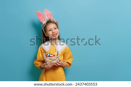 Cute little child wearing bunny ears on Easter day. Girl with painted eggs. Royalty-Free Stock Photo #2437403553