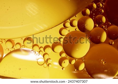 Yellow drops of oil or serum, and beer bubbles texture the background. Oil drops on the water's surface. Macro photography Royalty-Free Stock Photo #2437407307