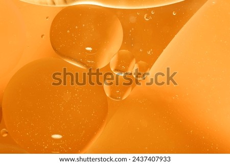 Yellow drops of oil or serum, and beer bubbles texture the background. Oil drops on the water's surface. Macro photography Royalty-Free Stock Photo #2437407933