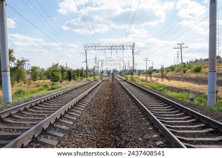 Side view of empty steel railroad tracks outdoors in a sunny summer day. Blue sky with some white clouds. Soft focus. Copy space for your text. Railway transportation theme.