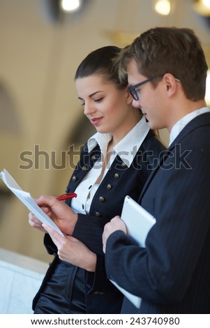Young business woman and businessman studying documents in the hallway