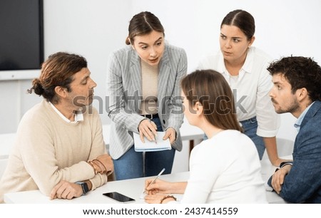 Emotional language teacher telling interesting stories to adult attentive students during class break in auditory