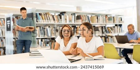 Student girls work together on project in the college library. High quality photo
