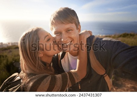 Hiking, kiss and fitness couple with selfie in nature for bonding, fun or romantic memory at sunset. Happy, love and people embrace for profile picture, photography or social media travel blog photo