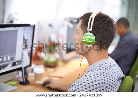 Business, designer and man with headphones at computer screen in office for creative internship and web design. Employee, rear view and monitor for multimedia production and video animation at desk Royalty-Free Stock Photo #2437431309