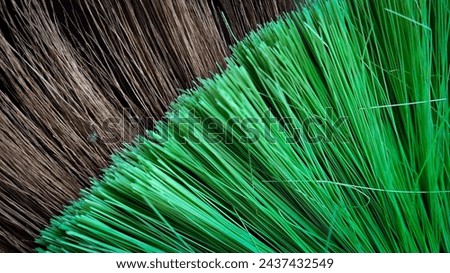 Close up photo of palm fibre broom and green plastic broom