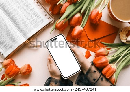 Phone with isolated screen on the background of the Bible and flowers.