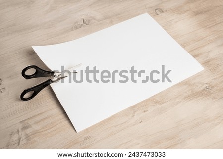 Paper cutting with scissors. A layout of a blank sheet of paper for assignments, a presentation of the design of paper crafts, a template. Royalty-Free Stock Photo #2437473033