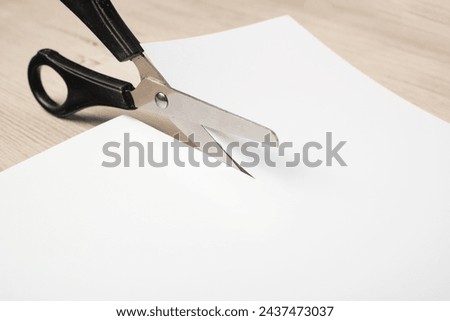 Paper cutting with scissors. A layout of a blank sheet of paper for assignments, a presentation of the design of paper crafts, a template. Royalty-Free Stock Photo #2437473037