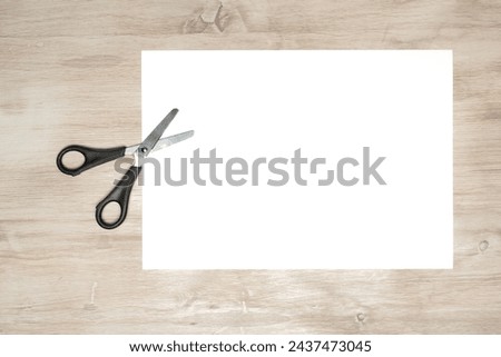 Paper cutting with scissors. A layout of a blank sheet of paper for assignments, a presentation of the design of paper crafts, a template. Royalty-Free Stock Photo #2437473045