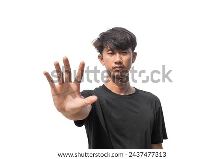 A young Asian man in his 20s wearing a black t-shirt on an isolated white background makes a stop gesture. A man raising his hand with five fingers spread