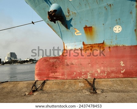 Port and ship, Anchor on large cargo ship's anchor being pulled. Blue and red ship, While docked at the pier by large ropes on the river, in the background is a view of the city and transport concept