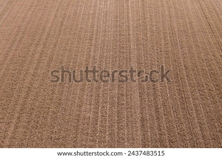 Aerial view displays vast farmland, where brown earth meets furrows in a mesmerizing dance of lines and symmetry.