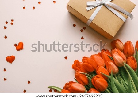 Gift box with a bow and a bouquet of red tulips, top view, background.