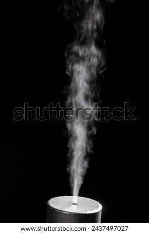Captivating image of a steady stream of smoke emanating from a cylindrical object, isolated against a dark background, resembling scientific or industrial testing Royalty-Free Stock Photo #2437497027