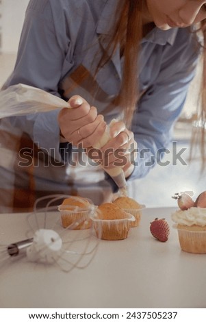 A female pastry chef decorates cupcakes with berries, showcasing her homemade baked goods. Explore the charm of home baking and small-scale business with this image of a skilled baker at work. Royalty-Free Stock Photo #2437505237