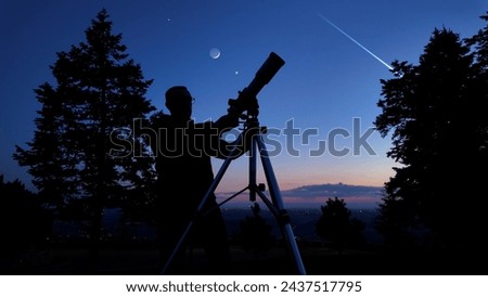 Amateur astronomer looking at the evening skies, observing planets, stars, Moon and other celestial objects with a telescope. Royalty-Free Stock Photo #2437517795
