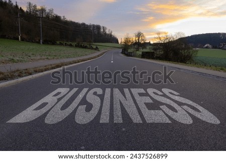 Asphalt road with arrow guideline and Business letters painted on the surface. An image of a road milestones are representative of success in the future goal. Road to success with light of the sun. Royalty-Free Stock Photo #2437526899