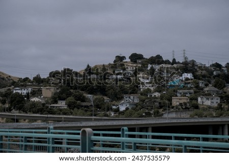 a picture of houses on a hill next to a highway on a cloudy day.