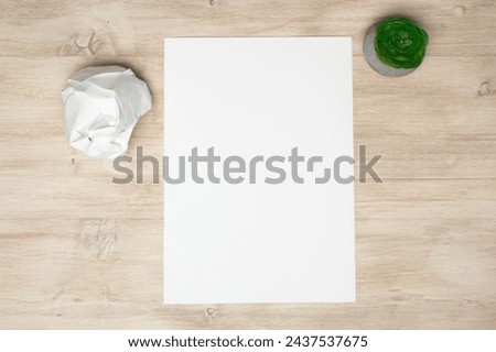 Top view, on a blank sheet of paper lying on a wooden table next to a crumpled sheet. A pen with a sheet of crumpled paper. Royalty-Free Stock Photo #2437537675