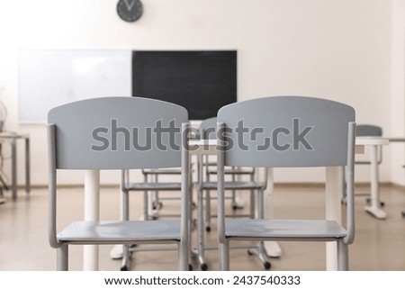 Empty school classroom with desks, blackboard and chairs